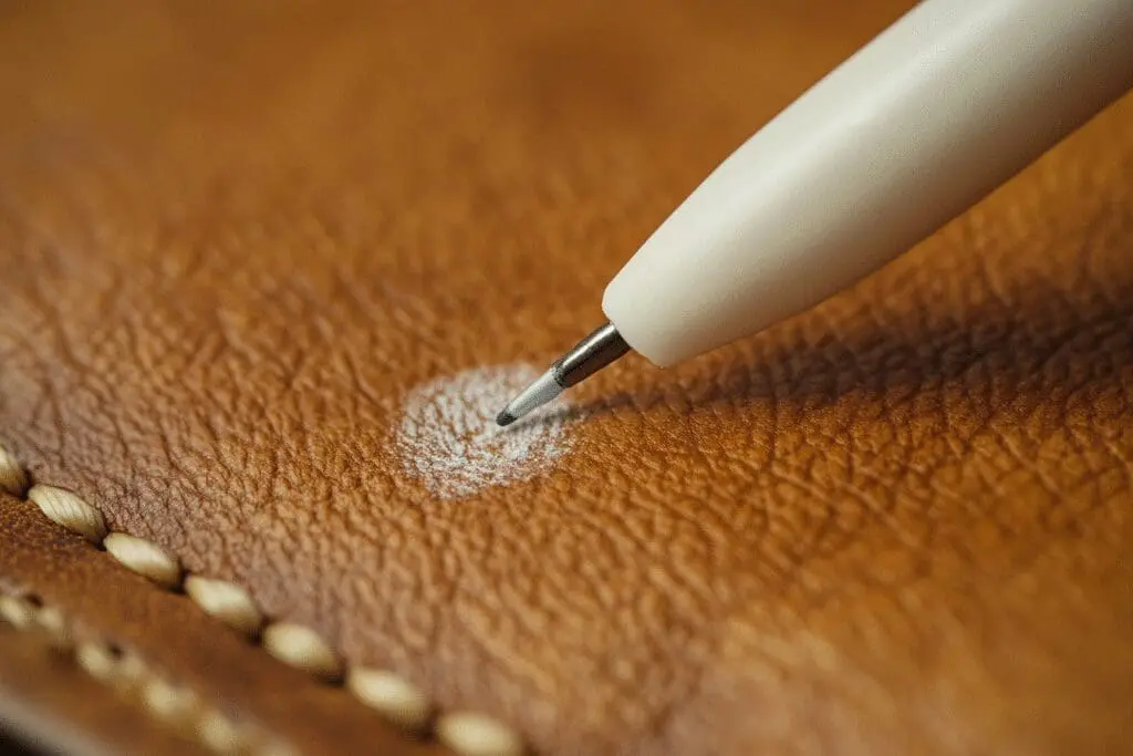 A Q-tip magically removes a pen mark from a leather surface, illustrating a surefire cleaning method