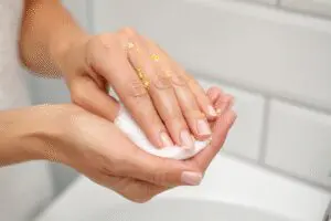 One of the top ways to learn how to get spray foam off hands safely and fast, showing oil being used to dissolve the residue
