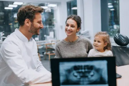 A parent's guide answering how old you have to be to get braces, showing a child and parent in a consultation with an orthodontist.