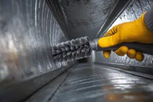 Critical steps for how to get rid of mold in air ducts, showing a professional technician cleaning inside a vent