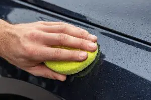 Fast hacks on how to get road paint off car surfaces, showing a clay bar gently lifting paint from a car's body