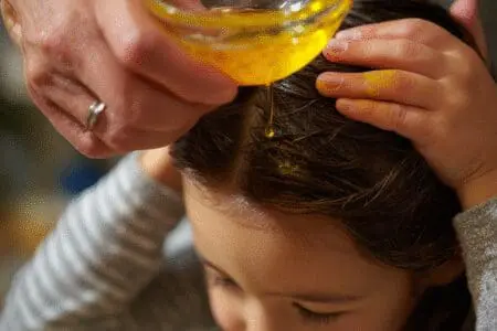 One of the top ways for how to get silly putty out of hair fast, showing a parent using oil to remove it from a child's hair