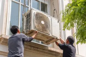 The #1 way on how to get rid of an air conditioner fast, showing a window unit being carefully removed from a home