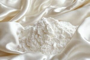 A pile of cornstarch sits on a delicate silk garment to absorb an oil stain, illustrating an expert tip.
